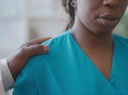 doctor intimidating a woman by holding her shoulder.